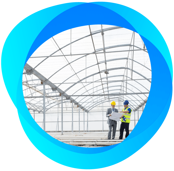 Round image surrounded in blue circles of 2 men in hard hats in new greenhouse facility analyzing blueprints.